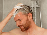 Mann schäumt sich Haar unter der Dusche ein