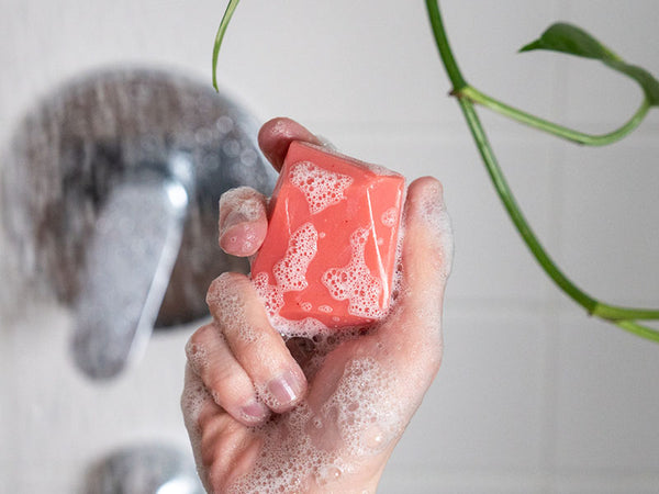 Hand hält schaumige feste Spülung in der Dusche