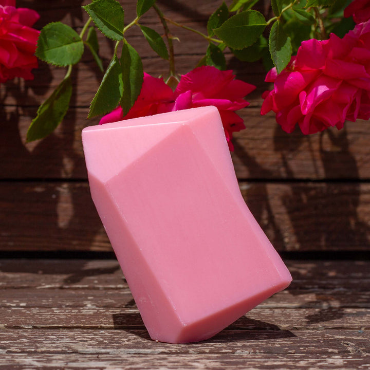 Pinker Heidi Himbeere Duschbrocken auf Holz mit Rosen im Hintergrund