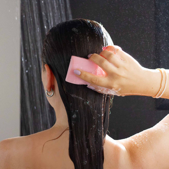 Frau wäscht ihr Haar in der Dusche mit dem festen Heidi Himbeere Duschbrocken